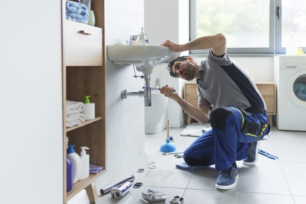 Professional plumber checking drain pipes at home and using pliers Image of a Professional plumber checking drain pipes at home and using pliers